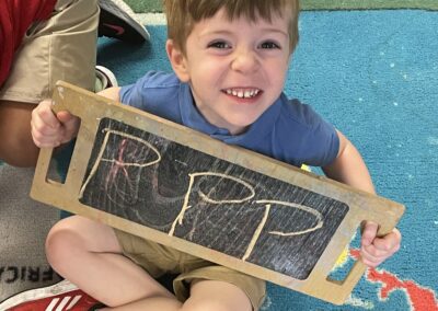 a boy holding a chalkboard with the letter p