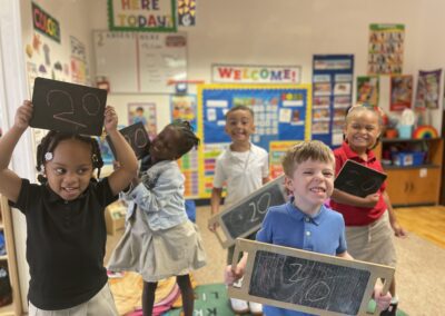 children holding chalkboards in a classroom